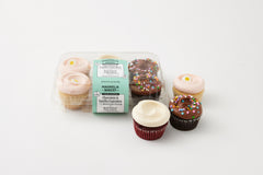 2 chocolate cupcake with chocolate buttercream and confetti sprinkles, 2 red velvet cupcakes, 2 vanilla cupcakes with pink buttercream icing with a flower decon in a plastic 6 pack container