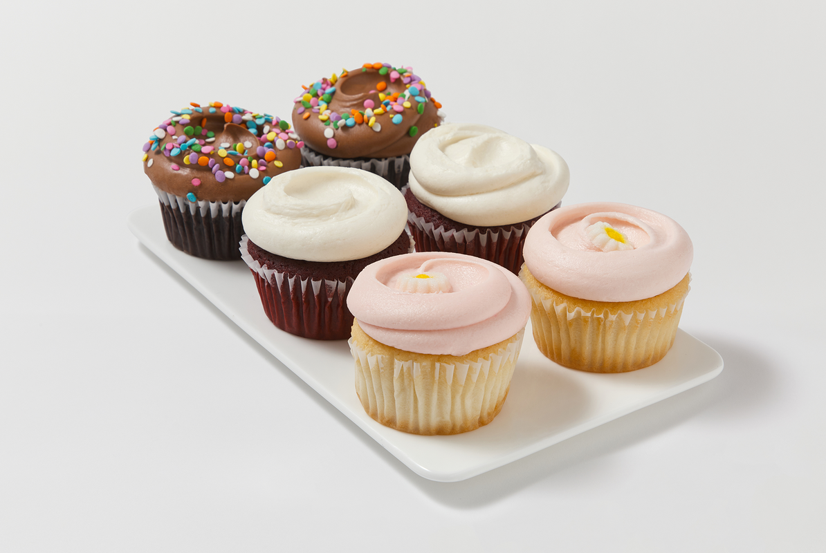 2 chocolate cupcake with chocolate buttercream and confetti sprinkles, 2 red velvet cupcakes, 2 vanilla cupcakes with pink buttercream icing with a flower decon