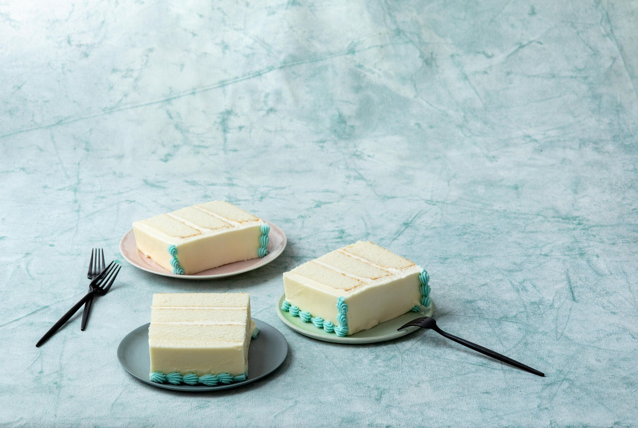 three vanilla cake slices from Magnolia Bakery on three plates