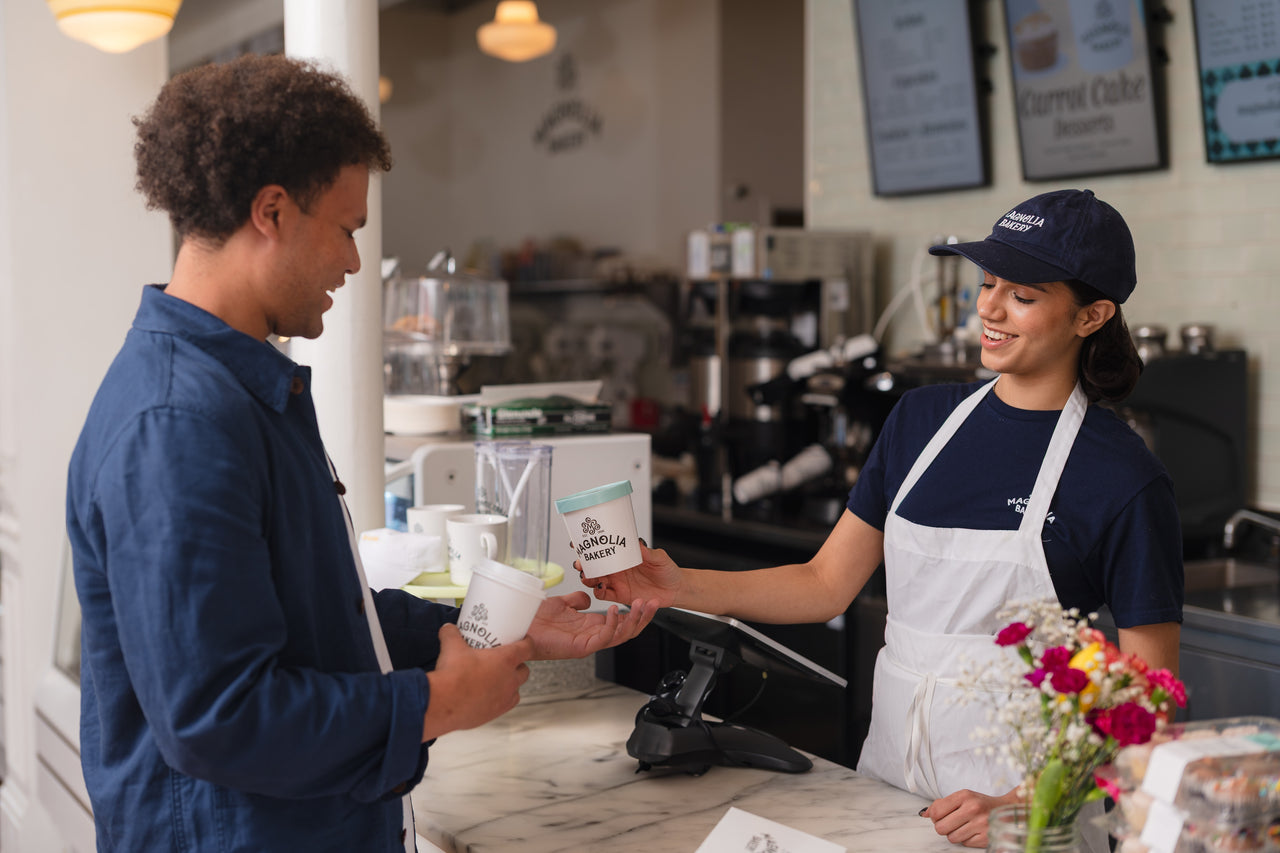 Customer receiving banana pudding from a Magnolia Bakery staff member